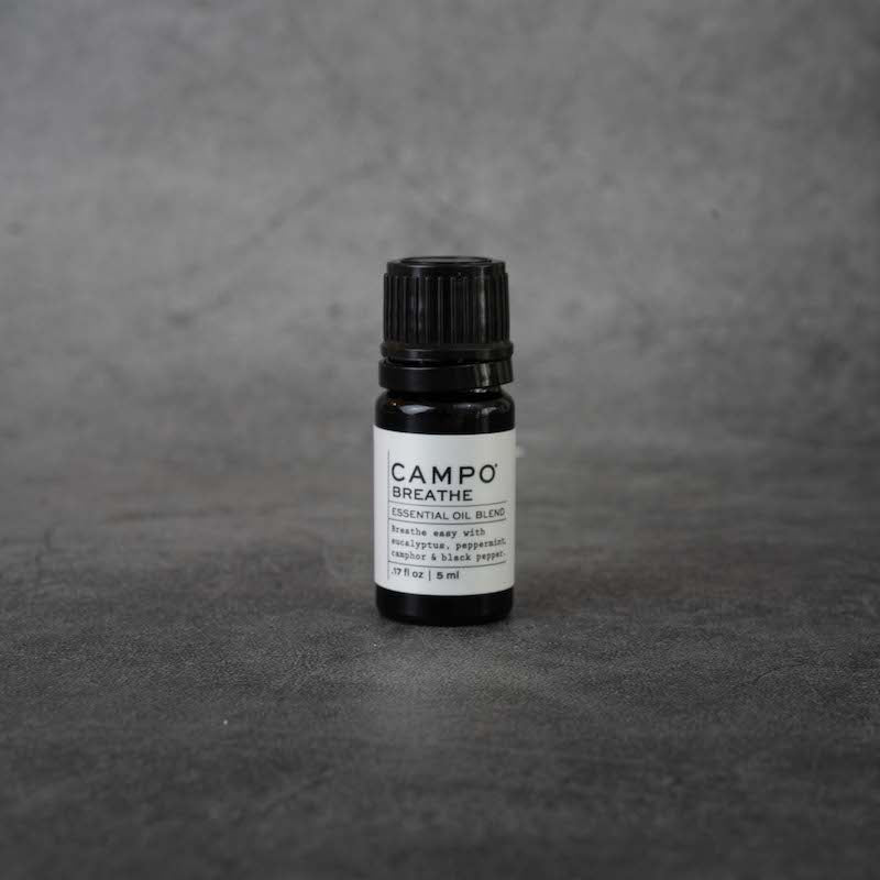 A small black bottle with a white label. The label reads "CAMPO Breathe, Essential oil blend, Breathe easy with eucalyptus, peppermint, camphor & black pepper, .17 fl oz, 5 ml" in black text. The bottle has a black twist-off lid.