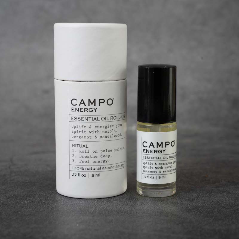 On the left: cylindrical packaging for the CAMPO Energy roll-on. The packaging is white and matches the label on the bottle, and has a pull-off cap. On the right: the same bottle as in the previous picture.