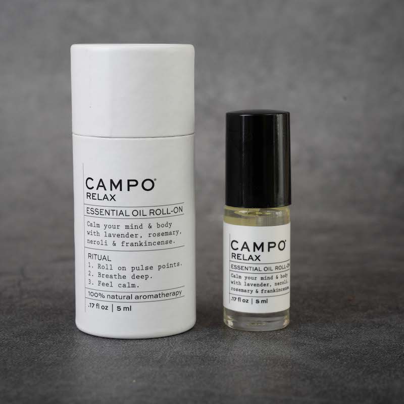 On the left: cylindrical packaging for the CAMPO Relax roll-on. The packaging is white and matches the label on the bottle. 