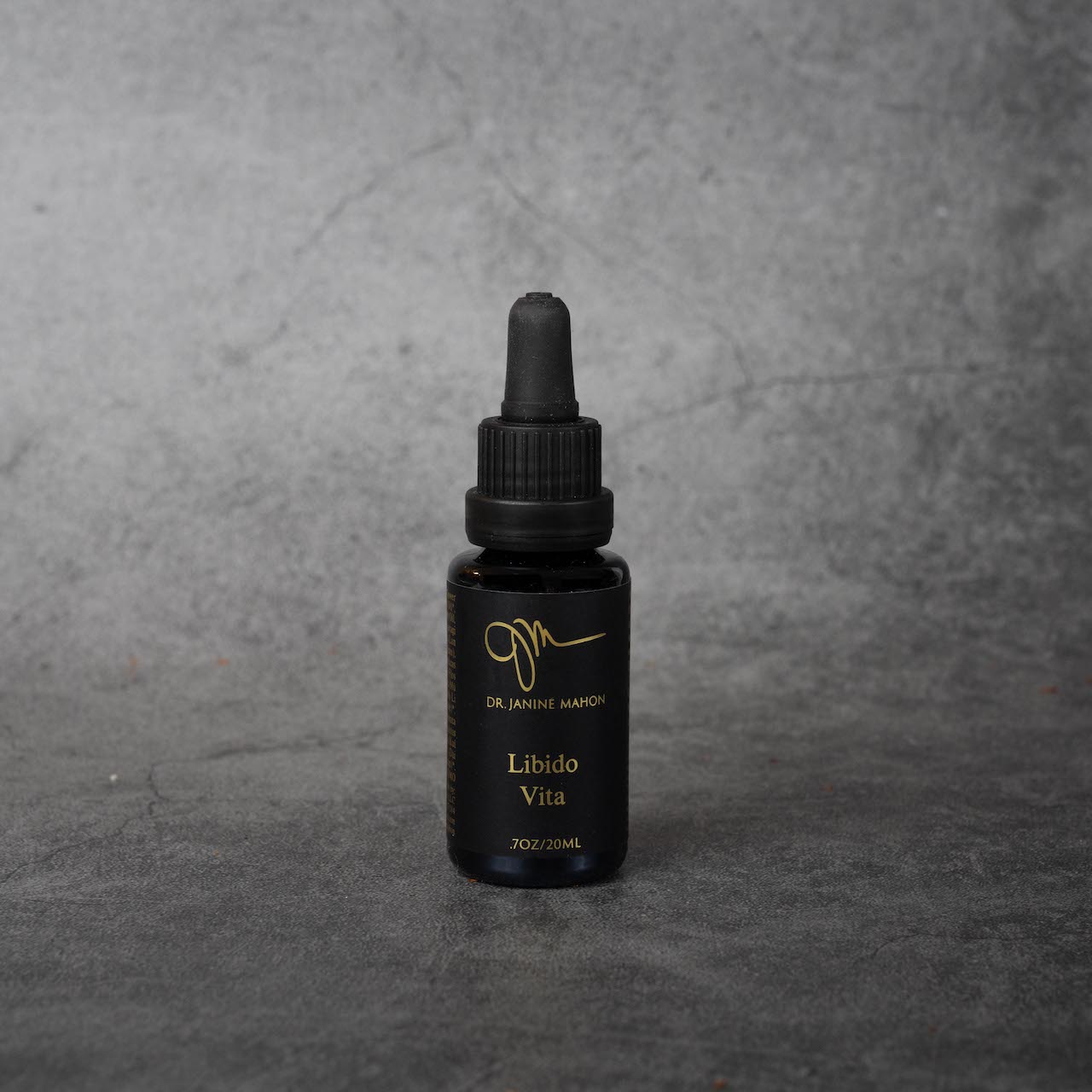 A small black bottle with gold lettering reading "Dr. Janine Mahon" in small print, and "Libido Vita, .70z/20ML" in slightly larger print. The bottle has a twist-off silicone dropper top.